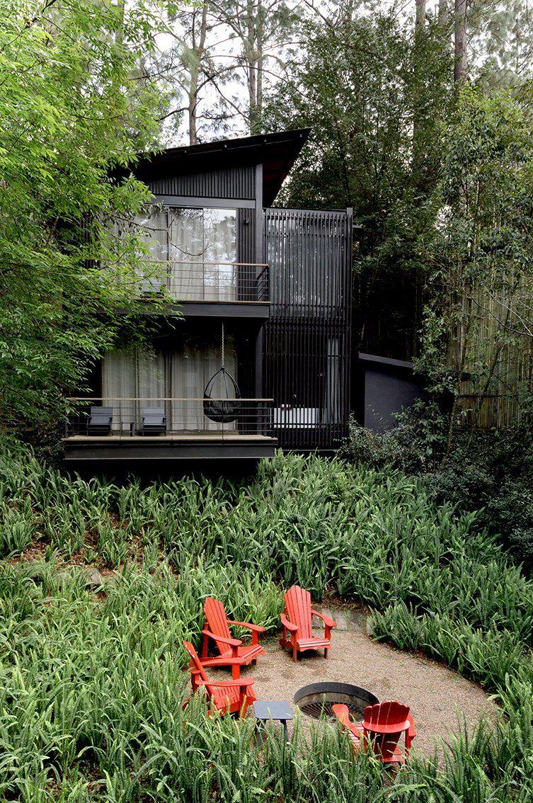 Cabaña en el bosque con sillas rojas alrededor de una fogata